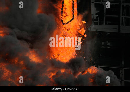 Drücken die rote heiße Koks aus dem Ofen nehmen. Stockfoto