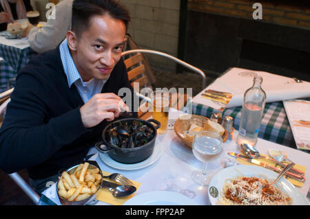 Asiatische Touristen Verkostung typische Gericht aus Brüssel: Muscheln und Pommes Frites. Belgien. Rue des Bouchers. Ein paar in eines der vielen r Stockfoto