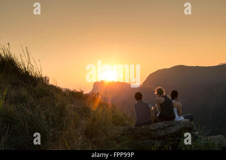 Drei Wanderer mit Blick auf den Sonnenaufgang Blick auf den Pedra Bonita im Tijuca Nationalpark, Rio de Janeiro, Brasilien Stockfoto