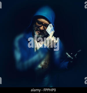 Porträt eines älteren Mannes mit Euro-Geld, trägt blaue Jacke. Hip Hop und urban Style. Stockfoto