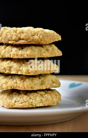 Haufen von hausgemachten Hafer Cookies auf Platte auf schwarzem Hintergrund Stockfoto