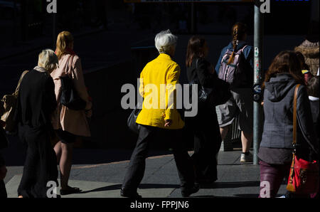 am frühen Morgen Sonnenlicht trifft Pendler in gelben Jacke in einer ansonsten tristen Umgebung in Brisbane Cbd Australien im Berufsverkehr Stockfoto