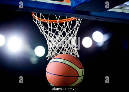 Basketball wird durch den Reifen bei einer Sportarena (vorsätzliche Spotlight) Stockfoto