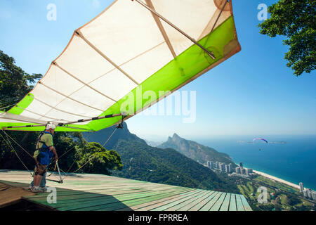 Brasilien, Rio, Tijuca-Wald, Drachenflieger, der sich auf den Start am Pedra Bonita-Felsen oberhalb des Strandes von Sao Conrado vorbereitet. Blick auf den Strand und den Atlantischen Ozean Stockfoto