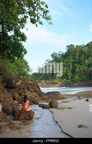 Eine Frau in ihren dreißiger Jahren, die am Strand von Ribeira Itacare, Bahia, Brasilien meditiert Stockfoto