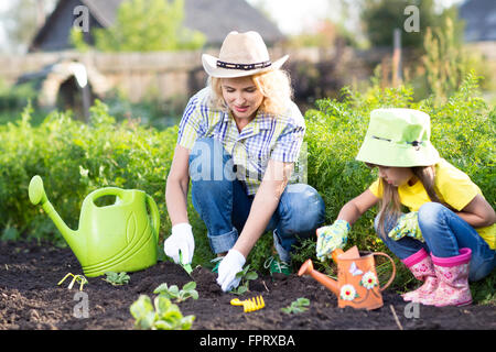 Kind mit Mutter Anpflanzen von Setzlingen im Garten Stockfoto