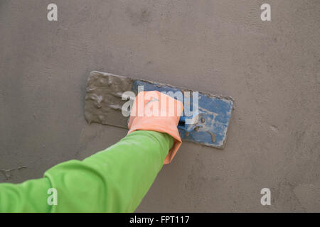 Nahaufnahme der Hand mit der Kelle ins nasse Betonmauer auf Baustelle Stockfoto