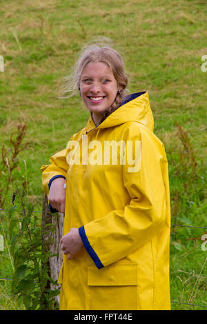 Glückliches Mädchen in der Natur tragen einen gelben Regenmantel Stockfoto