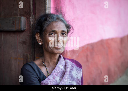 Lächelnde Indianerin gekleidet in lila Sari saß eine rosa Wand außerhalb Landhaus Stockfoto