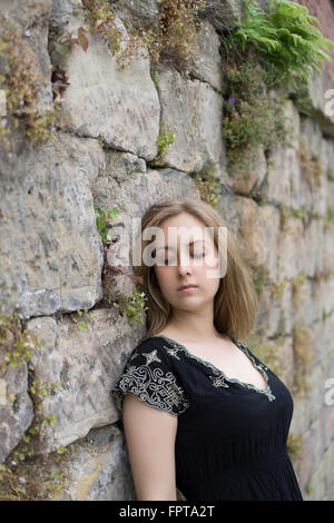 Traurige junge Frau lehnt sich an die Wand im freien Stockfoto