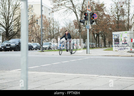 Junger Mann mit dem Fahrrad in der Stadt durch die rote Ampel, München, Bayern, Deutschland Stockfoto