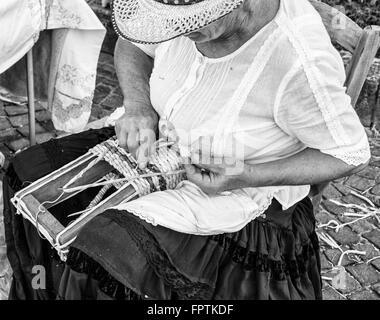 Ältere Dame baut Taschen mit den getrockneten Blättern der Maiskolben von Hand gewebt. Stockfoto