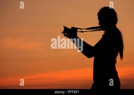 Silhouette der Frau Aufnahmen mit einer Kamera bei Sonnenuntergang Stockfoto