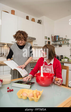 Zwei ältere Frau Vergleich Rezept auf digital-Tablette und Kochbuch, München, Bayern, Deutschland Stockfoto
