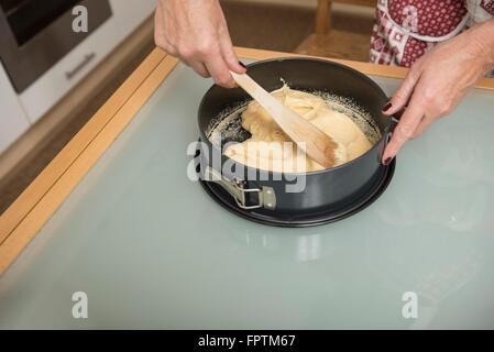 Ältere Frau Teig in einer Pfanne Spring Form füllen und glatt, München, Bayern, Deutschland Stockfoto