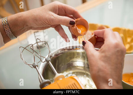 Ältere Frau teilt, Eiweiß und Eigelb in Küche, München, Bayern, Deutschland Stockfoto