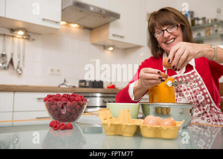 Ältere Frau teilt, Eiweiß und Eigelb in Küche, München, Bayern, Deutschland Stockfoto