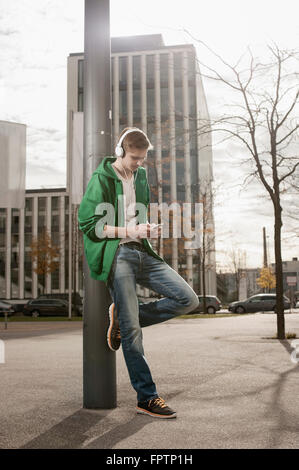 Teenager wartet auf jemanden und hören Sie Musik in der Straße, Bayern, Deutschland Stockfoto