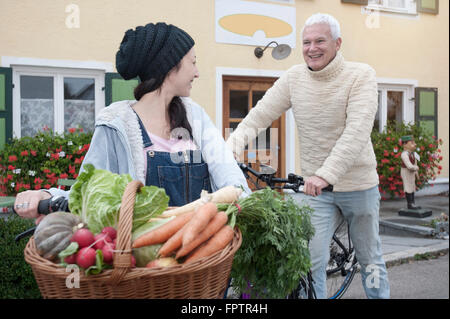 Paar mit Fahrrädern und Gemüse gehen auf der Straße vor Vollwertkost Shop, Bayern, Germany Stockfoto