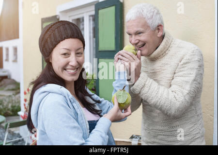 Portrait des weiblichen Verkäuferin gibt Quitte an Client für riechen, Bayern, Deutschland Stockfoto