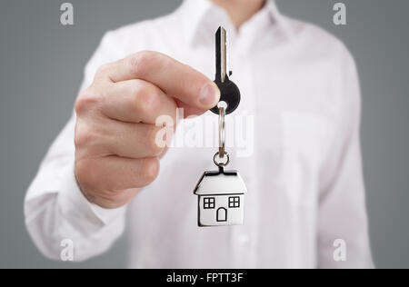 Mann hielt Hausschlüssel auf einem Haus geformt Schlüsselbund Stockfoto