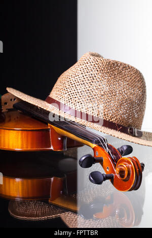 Alte Geige und Strohhut isoliert auf schwarzen und weißen Hintergrund und Glas Schreibtisch Stockfoto