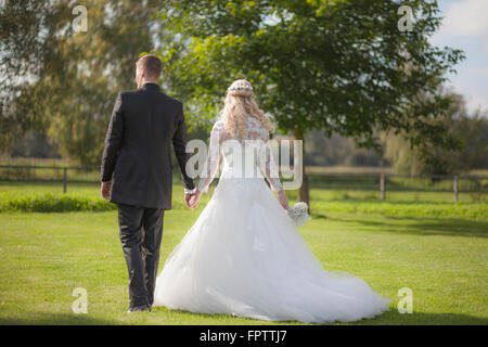 Rückansicht des ein Brautpaar zu Fuß auf dem Rasen, Ammersee, Upper Bavaria, Bavaria, Germany Stockfoto