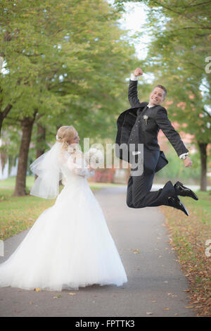 Braut hält Blumenstrauss und Bräutigam springen in Allee, Ammersee, Upper Bavaria, Bavaria, Germany Stockfoto