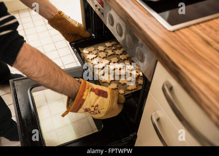 Nahaufnahme eines Mannes herausnehmen gebackene Plätzchen aus dem Ofen, München, Bayern, Deutschland Stockfoto