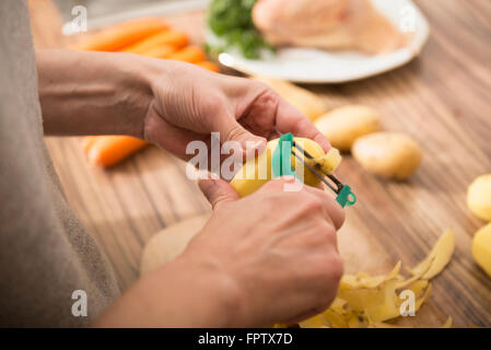 Frau, die Kartoffeln schälen, mit einem Sparschäler in Küche, München, Bayern, Deutschland Stockfoto