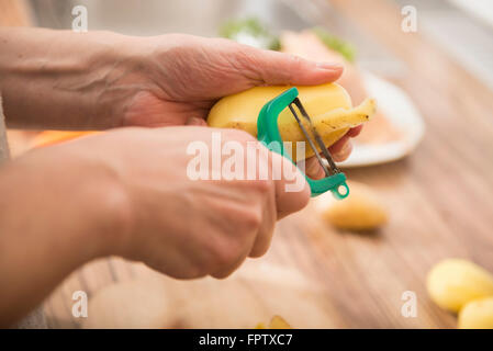 Frau, die Kartoffeln schälen, mit einem Sparschäler in Küche, München, Bayern, Deutschland Stockfoto