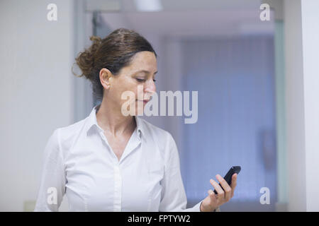 Weibliche Physiotherapeut lesen Nachricht auf einem Mobiltelefon, Freiburg Im Breisgau, Baden-Württemberg, Deutschland Stockfoto