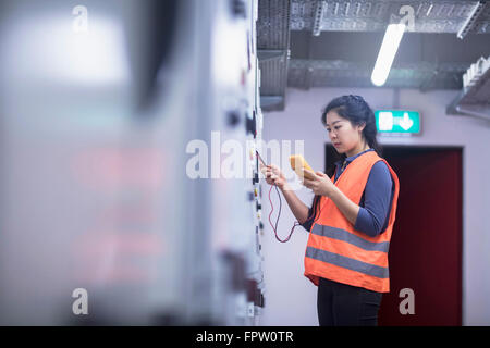 Junge Ingenieurin Prüfung Bedienfeld mit Multimeter in einer Industrieanlage, Baden-Württemberg, Deutschland Stockfoto