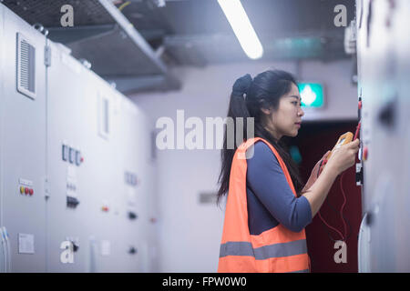 Junge Ingenieurin Prüfung Bedienfeld mit Multimeter in einer Industrieanlage, Baden-Württemberg, Deutschland Stockfoto