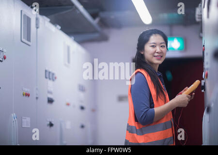 Junge Ingenieurin Prüfung Bedienfeld mit Multimeter in einer Industrieanlage, Baden-Württemberg, Deutschland Stockfoto