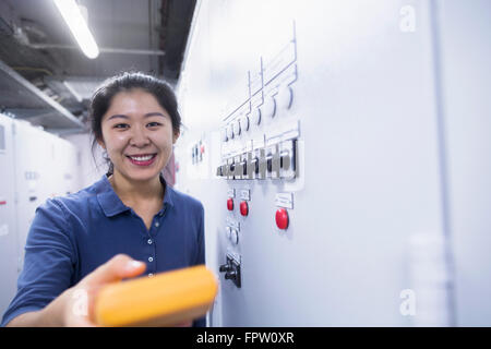 Junge Ingenieurin Prüfung Bedienfeld mit Multimeter in einer Industrieanlage, Baden-Württemberg, Deutschland Stockfoto