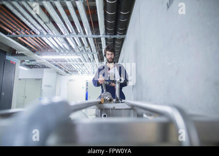 Junge männliche Ingenieur Überprüfung Pipelineanbindung in einer Industrieanlage, Freiburg Im Breisgau, Baden-Württemberg, Deutschland Stockfoto