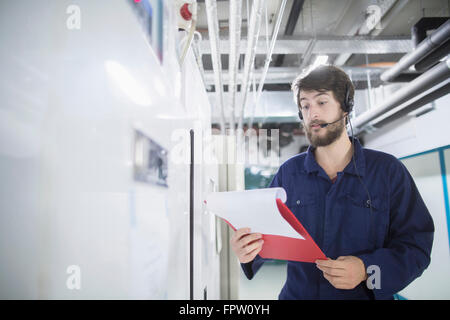 Junge männliche Ingenieur tragen Kopfhörer und arbeiten in einer Industrieanlage, Freiburg Im Breisgau, Baden-Württemberg, Deutschland Stockfoto