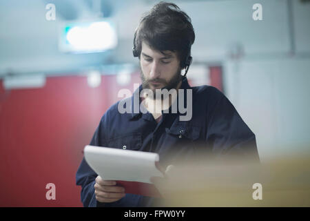 Junge männliche Ingenieur tragen Kopfhörer und arbeiten in einer Industrieanlage, Freiburg Im Breisgau, Baden-Württemberg, Deutschland Stockfoto