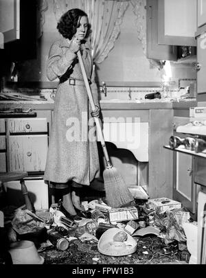 1930ER JAHREN NOTLEIDENDE FRAU FEGT ESSEN UND MÜLL IN KÜCHE NACHMAHD DES 10. MÄRZ 1933 ERDBEBEN LONG BEACH CA USA Stockfoto