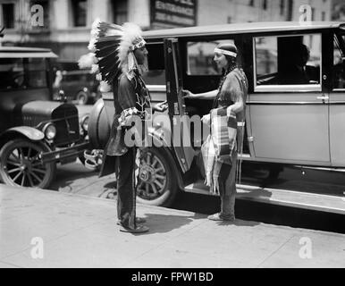 1930ER JAHREN NATIVE AMERICAN INDIAN PAAR TRAGEN TRADITIONELLE KLEIDUNG MANN IN FEDER KOPFSCHMUCK UND FRAU INS AUTO TAXI CAB Stockfoto