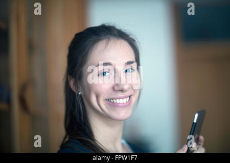 Porträt einer jungen Frau hält digital-Tablette und lächelnd, Freiburg Im Breisgau, Baden-Württemberg, Deutschland Stockfoto