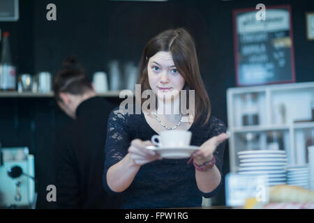 Junge Kellnerin serviert Kaffee in Coffee-Shop, Freiburg Im Breisgau, Baden-Württemberg, Deutschland Stockfoto