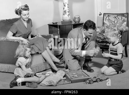 1940ER JAHRE FAMILIE VATER MUTTER TOCHTER SOHN ZUSAMMEN IM WOHNZIMMER MIT SPIELZEUG-ERECTOR-SET Stockfoto