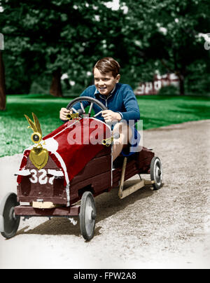 1930ER JAHRE JUNGE NACH HAUSE FAHREN GEBAUT RENNWAGEN MIT LENKRAD Stockfoto