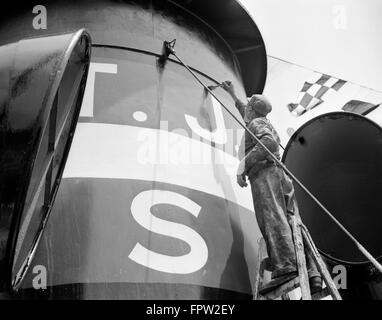 1930ER JAHRE MANN MALER MALEREI SCHORNSTEIN AUF BOOT BESATZUNG HÄLT PINSEL ZU ERREICHEN STEHT AUF LEITER Stockfoto