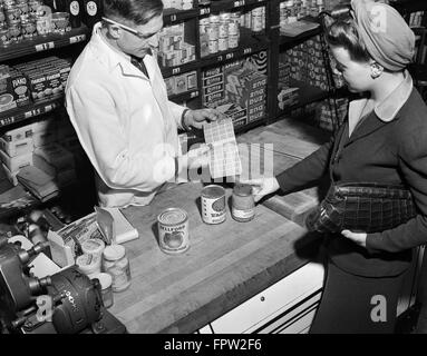 1940ER JAHREN FRAU EINKAUF KANN GÜTER ZÄHLEN RATION COUPONS MARKENBUCH IN NACHBARSCHAFT LEBENSMITTELGESCHÄFT NEW YORK CITY USA Stockfoto