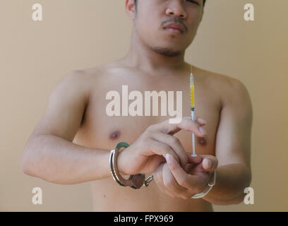 junger Mann hält Syring in der hand mit Handschellen Stockfoto