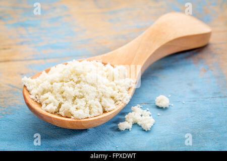 Molke-Protein-Pulver auf einem Holzlöffel gegen blau lackierten Grunge Holz Stockfoto