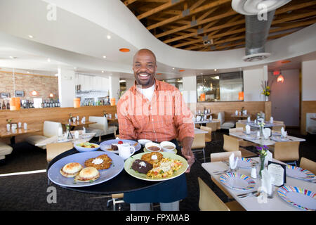 Kellner, Stacy Jones, serviert einige leckere Brunch-Platten im stilvollen South Congress Cafe in Austin, Texas, USA Stockfoto